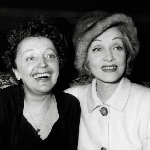 Das Bild zeigt Edith Piaf und Marlene Dietrich, die in die Kamera lächeln