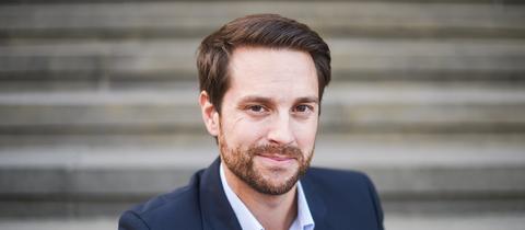 Mirko Drotschmann alias "MrWissen2Go" sitzt auf einer Treppe am Berliner Gendarmenmarkt