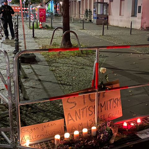 Brennende Kerzen stehen vor Schildern mit der Aufschrift «Stop Antisemitismus» an dem abgesperrten Bürgersteig vor dem jüdischen Gemeindezentrum an der Brunnenstraße nach dem versuchten Brandanschlag auf die Synagoge in der Berliner Brunnenstraße