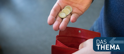 Münzen im Wert von fünf Euro werden über ein rotes Portemonnaie gehalten