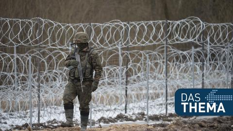 Ein polnischer Soldat patroulliert an der Grenze zu Belarus vor einem Stacheldrahtzaun.