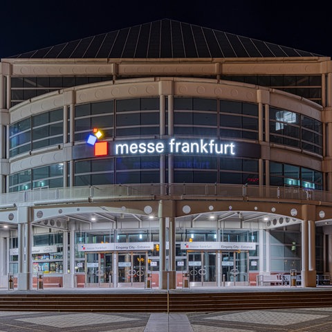 Der beleuchtete Haupteingang der Messe Frankfurt am Abend.