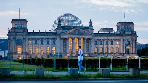 Ein Passant geht morgens am Reichstagsgebäude vorbei.