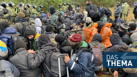 Migranten sitzen zusammen vor der Grenze in Belarus am gesperrten Übergang zu Polen