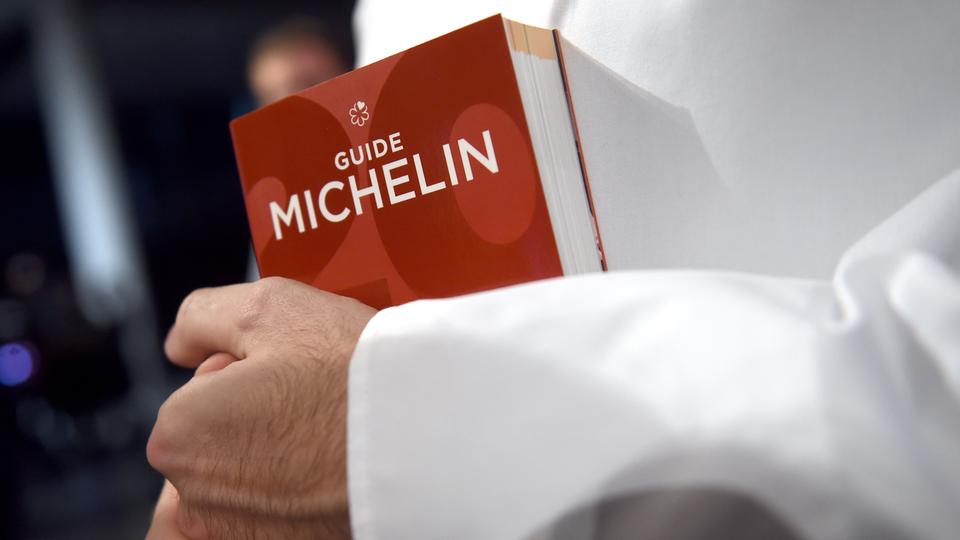Ein Koch hält den Guide Michelin im Arm