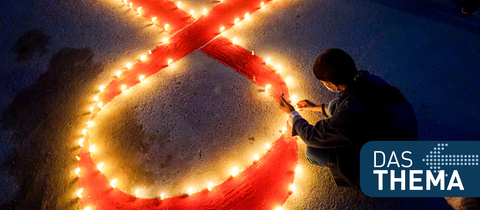 Eine Frau stellt auf einer Veranstaltung im Vorfeld des Welt-Aids-Tags Kerzen auf, die eine rote Schleife formen - ein weltweit anerkanntes Symbol für die Solidarität mit HIV-Infizierten. 