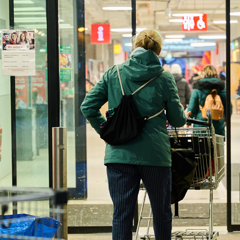 Frau schiebt einen Einkaufswagen in den Supermarkt
