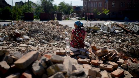 Eine Frau ruht sich aus, während sie die Trümmer eines Tempels wegräumt, der bei Angriffen in Gorenka am Stadtrand von Kiew zerstört wurde.