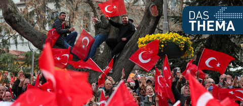 Menschen schwenken auf einer Wahlkampf-Veranstaltung türkische Flaggen