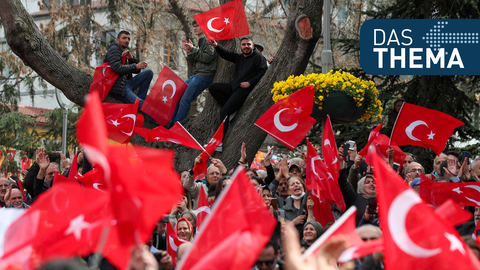 Menschen schwenken auf einer Wahlkampf-Veranstaltung türkische Flaggen