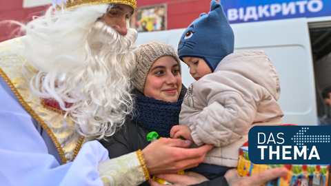 Auch in der Ukraine wird versucht, ein wenig weihnachtliche Stimmung zu verbreiten. Ein als Sankt Nikolaus verkleideter Mann übergibt einem Kind in Cherson ein Geschenk