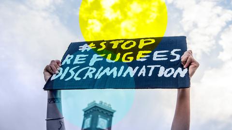 Zwei Hände halten ein Schild mit der Aufschrift "Stop Refugees Discrimination"