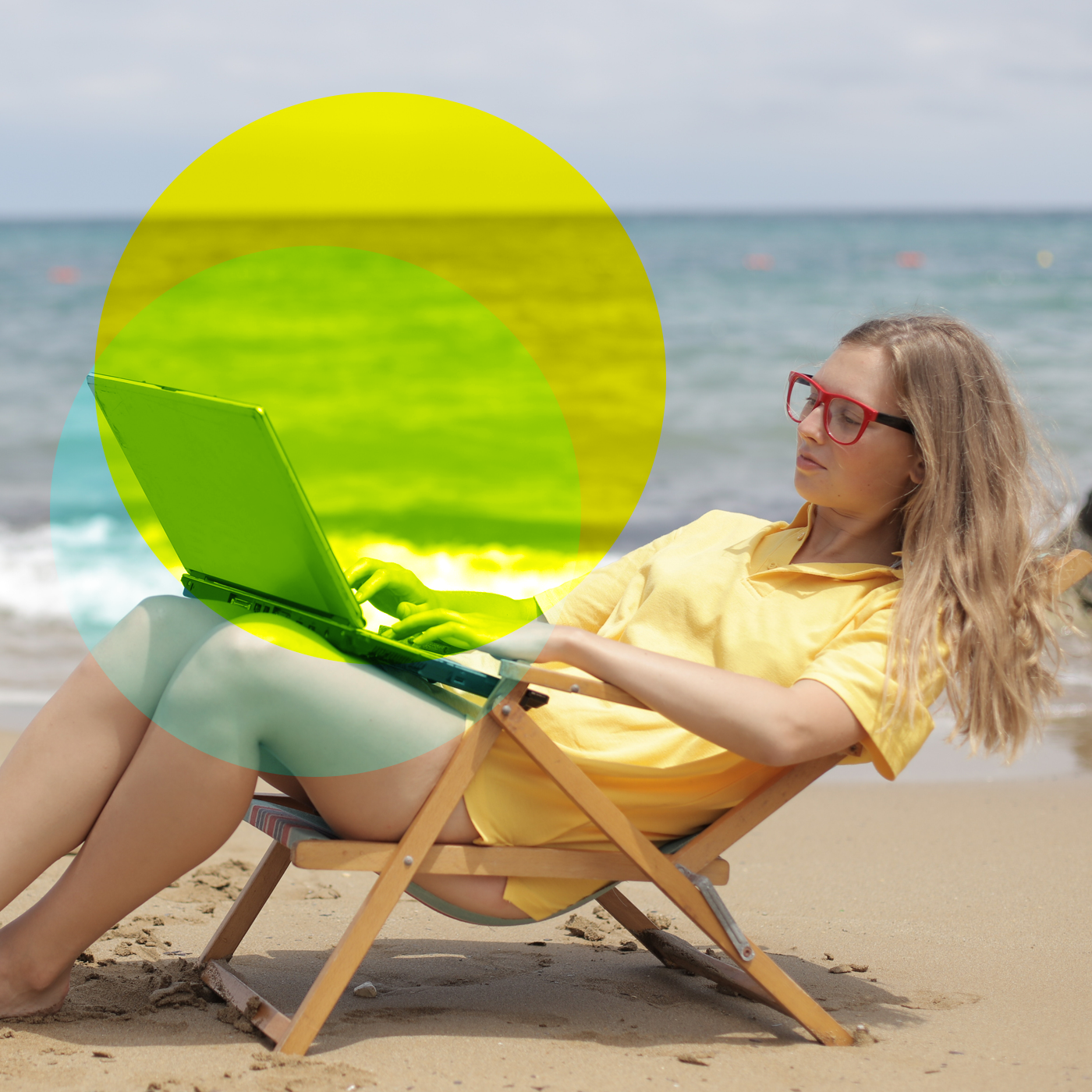 Frau liegt mit Laptop im Liegestuhl am Strand