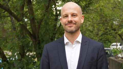David Fuhr von der Firma HiSolutions vor einem grünen Baum