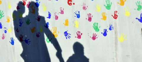 Schatten von einem Erwachsenen, der ein Kind an der Hand hält