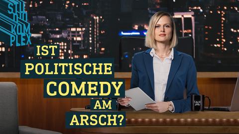 Hostess Anne steht als Late-Night-Moderatorin am Schreibtisch und schaut in die Kamera. Sie hält ihr Skript in der Hand und führt durch die Sendung. 