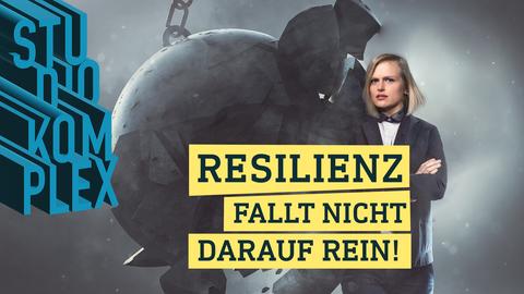 Die Hostin Anne blickt stark und unbeirrt in die Kamera während eine riesige Abrisskugel gegen sie aufprallt. Die Kugel zerschmettert an ihr, doch Anne hält mit unveränderter Haltung stand