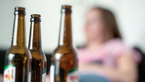Frau sitzt hinter mehreren Bierflaschen