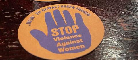 Oranger Bierdeckel mit der Aufschrift "Nein zu Gewalt gegen Frauen"