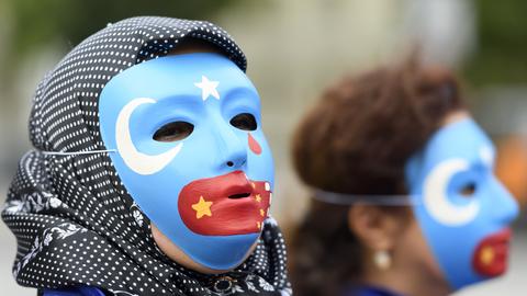 Personen mit Uiguren-Masken demonstrieren gegen die Unterdrückung der Minderheit in China