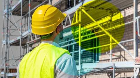 Mann mit Helm steht vor einer Baustelle