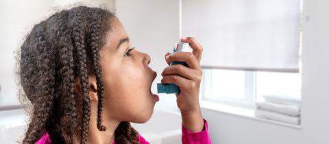 Symbolbild: Ein junges Mädchen führt ihren Inhalator an den Mund