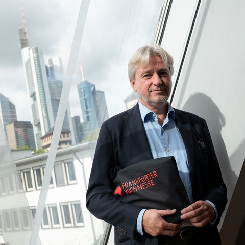 der Direktor der Buchmesse Jürgen Boos auf dem Frankfurter Messegelände mit der Skyline im Hintergrund