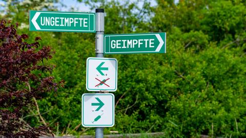 Smybolbil: Zwei Wegweiser deuten in entgegengesetzte Richtungen. Auf einem steht "geimpft", auf dem anderen "ungeimpft".
