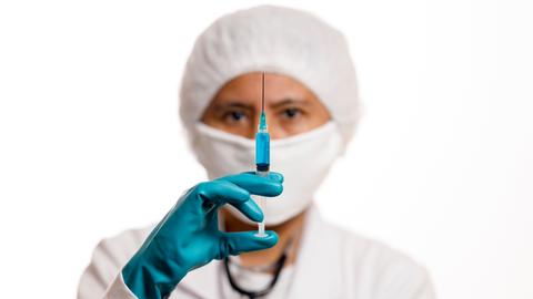 Symbolbild: Eine Ärztin hält eine aufgezogene Spritze in die Kamera