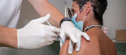 Eine Frau bekommt eine Corona-Impfung in den linken Oberarm gespritzt. 