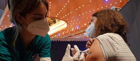 Eine Frau lässt sich von einer Helferin in einer Kölner Tazschule impfen