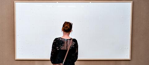 Eine Frau steht vor einem leeren Bilderrahmen im Kunsten Museum in Aalborg.
