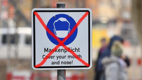 Symbolbild: Ein Warnschild, dass Masken getragen werden müssen, ist durchgestrichen