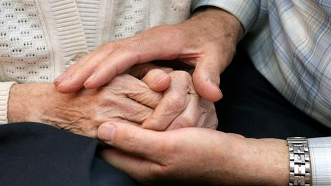 Sujetbild: Männerhände umfassen die Hände einer Seniorin.