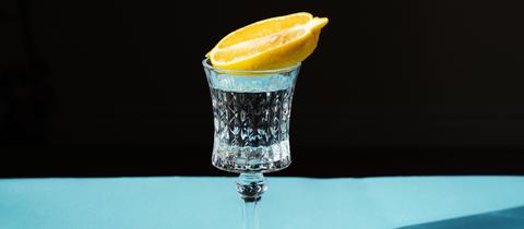 Auf einem Glas Tequila liegt eine halbe Limone
