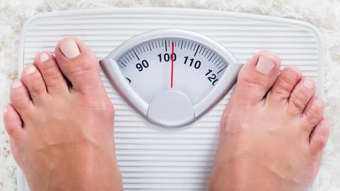 Ein paar Füße auf einer Waage, die etwas mehr als 100 Kilogramm anzeigt