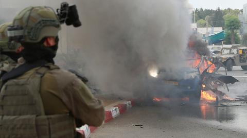 Israeli soldiers try to extinguish a burning vehicle in Sderot, southern Israel