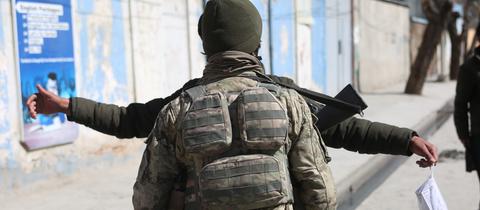 Ein Mitglied der afghanischen Sicherheitskräfte durchsucht einen Mann an einem Sicherheitskontrollpunkt während einer Räumungsaktion. 