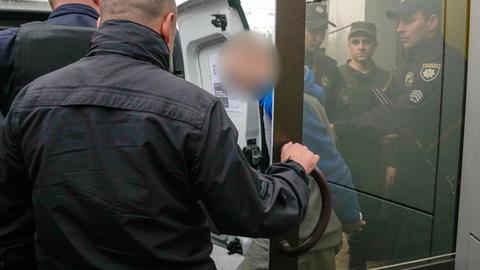 Ein russischer Soldat (M) wird von Polizisten nach einer Gerichtsverhandlung in Kiew begleitet. Der 21-Jährige hatte vor Gericht in der ukrainischen Hauptstadt ausgesagt, auf Befehl einen 62-Jährigen Zivilisten im Dorf Tschupachiwka im Gebiet Sumy erschossen zu haben. 