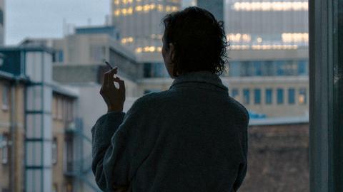Eine rauchende Frau steht am Fenster