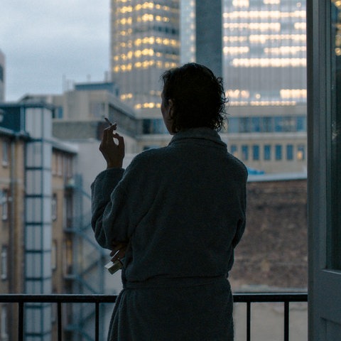 Eine rauchende Frau steht am Fenster