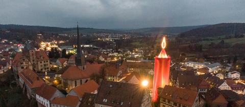 Die „größte Adventskerze der Welt“ leuchtet über der Altstadt von Schlitz. Traditionell wird dazu ein 35 Meter hoher Turm zur Adventszeit rot verhüllt.