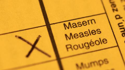 Ein Impfpass mit einem Kreuz bei der Masern-Impfung liegt auf einem Tisch.