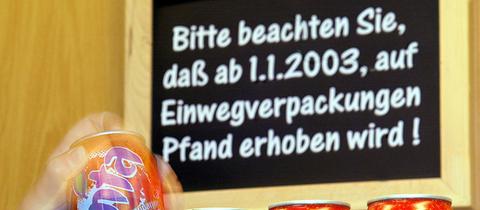 Über den Getränkedosen in einem Supermarkt hängt ein Schild, das die Kunden auf das neue Pfand auf Einwegverpackungen aufmerksam macht