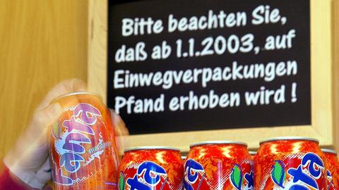 Über den Getränkedosen in einem Supermarkt hängt ein Schild, das die Kunden auf das neue Pfand auf Einwegverpackungen aufmerksam macht