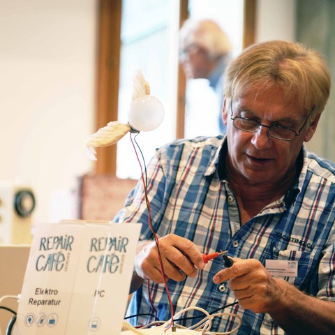 Mann in einem Repair-Café repariert Elektrogeräte