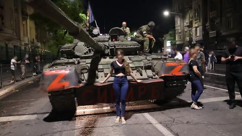 Eine Frau posiert vor einem Panzer der Wagner Gruppe