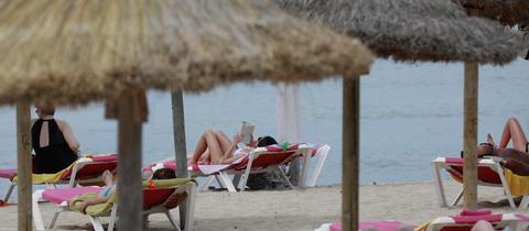 Menschen genießen die warmen Temperaturen am Strand in dem Badeort S`Arenal auf der Baleareninsel Mallorca