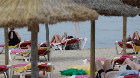 Menschen genießen die warmen Temperaturen am Strand in dem Badeort S`Arenal auf der Baleareninsel Mallorca