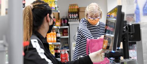 Eine Frau packt ihre Einkäufe an einer Supermarktkasse in eine Stofftasche